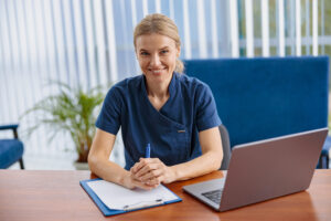 A nurse sitting in front of a computer learning how to become a legal nurse consultant