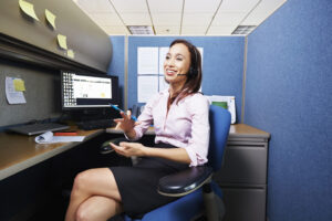An image of an in-house legal nurse consultant working at an office desk speaking on a telephone headset. 