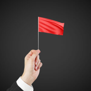 A hand holding up a red flag, indicating problems with a medical record