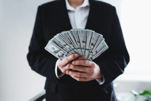 Subcontractor LNC Pay and Tax considerations Image of a subcontracting LNC holding a handful of hundred dollar bills.